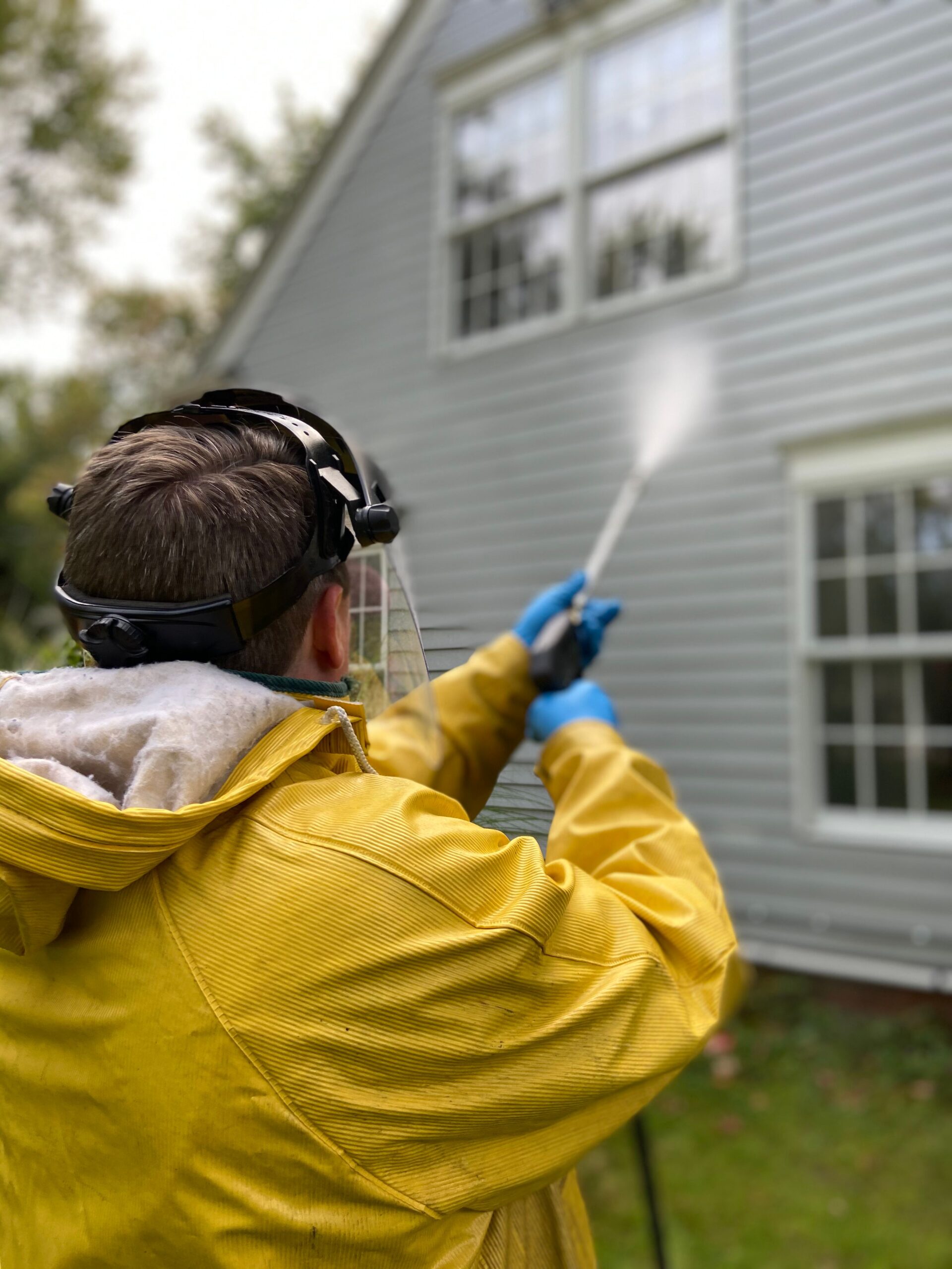Technician pressure washing residential siding
