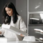 Customer opening a long white parcel in a quiet kitchen