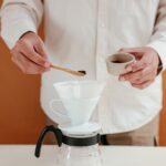 Hands preparing pour-over coffee with a ceramic dripper