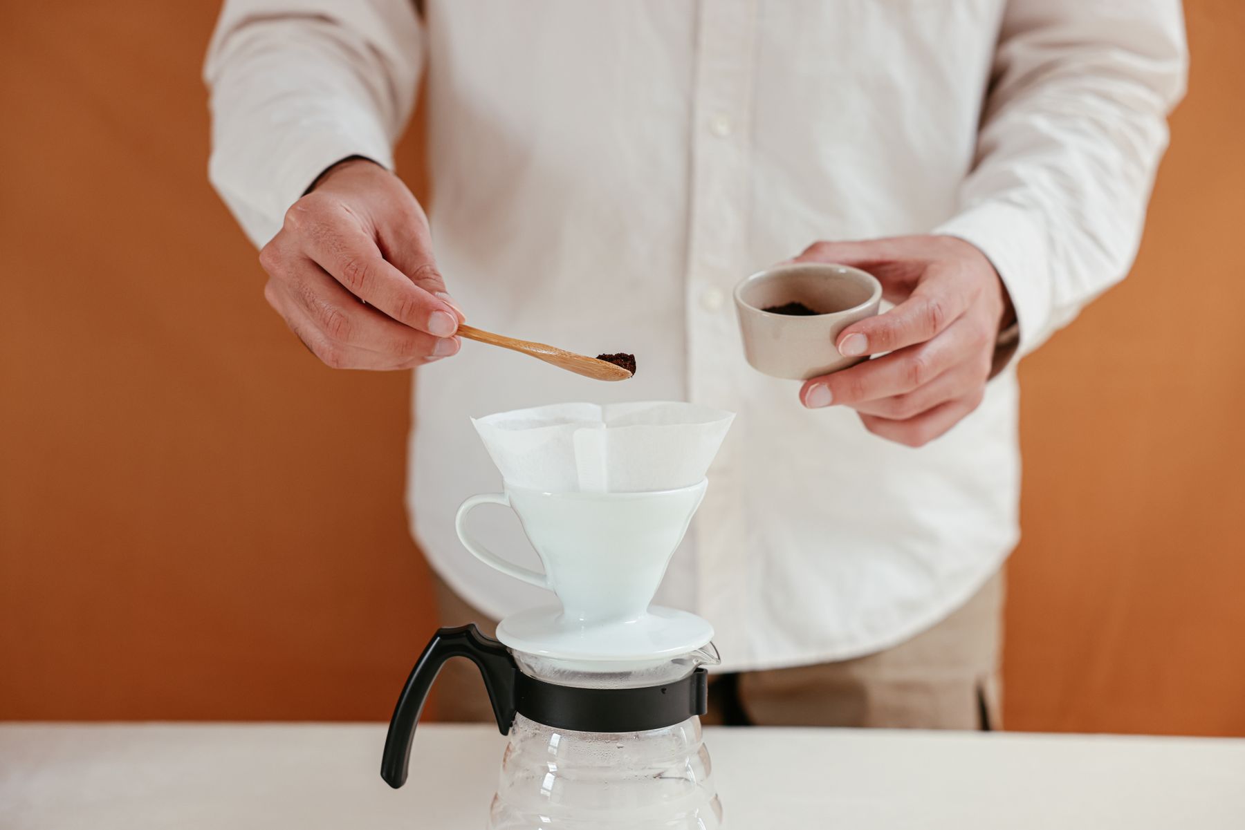 Hands preparing pour-over coffee with a ceramic dripper