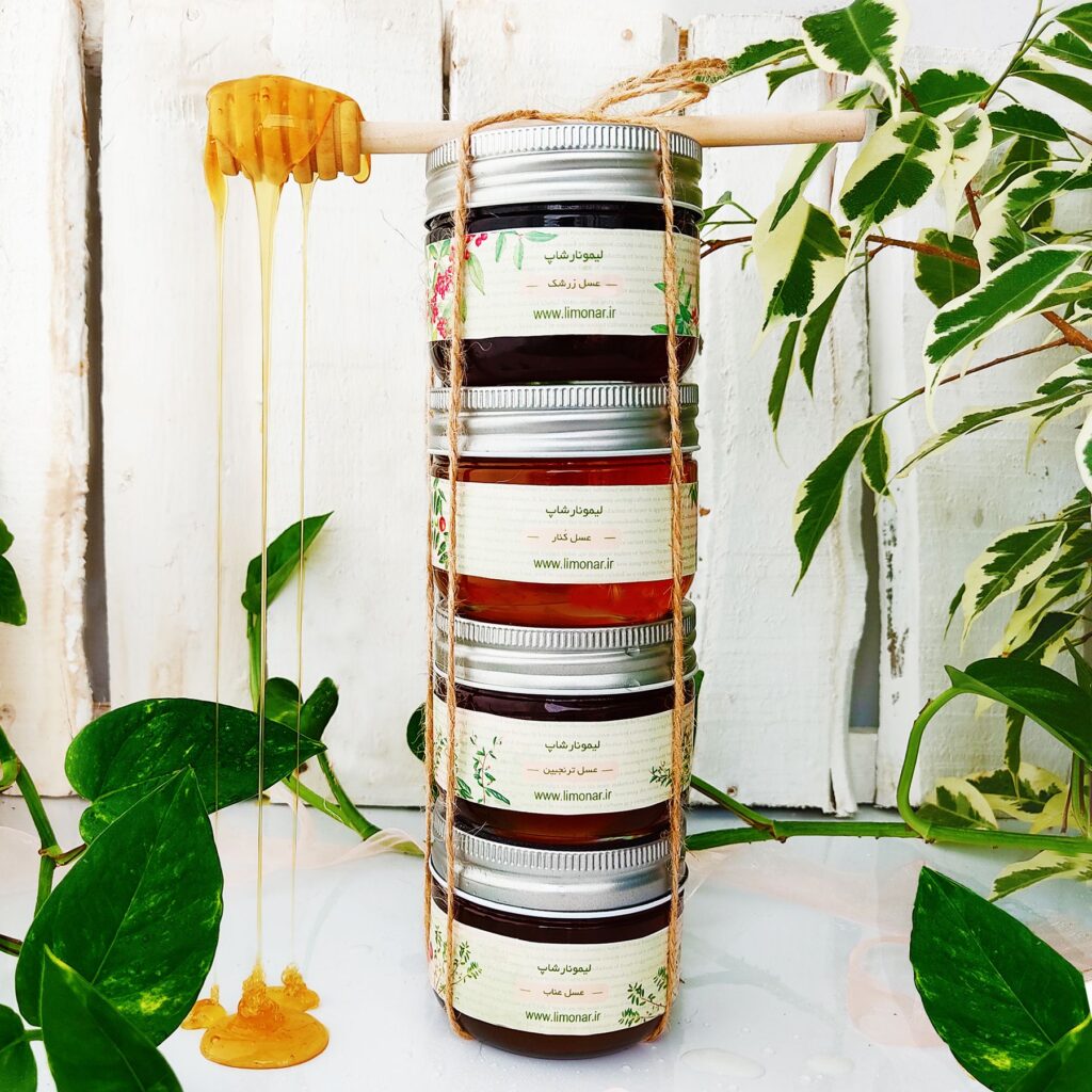 Stacked jars of honey with green leaves and a wooden dipper