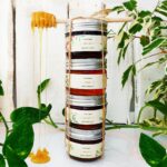 Stacked jars of honey with green leaves and a wooden dipper